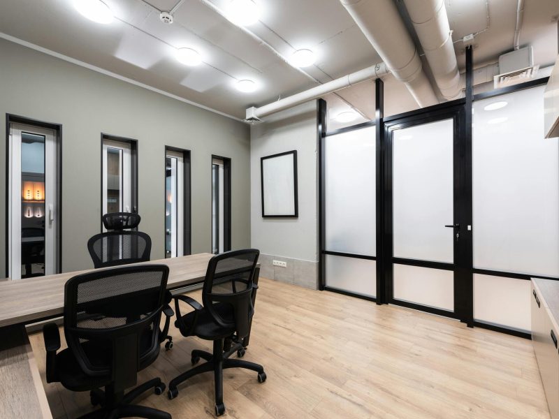 wooden-table-and-black-office-chairs-placed-in-spacious-room-in-new-contemporary-workplace-5ysYotOmy4ZLNgCDk3ZHPg